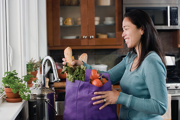 woman in kitchen unpacking groceries
