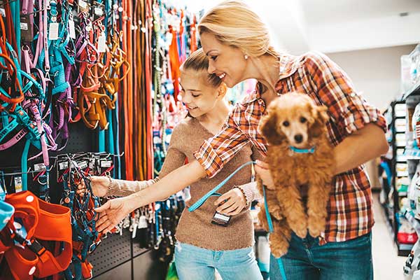 mother, daughter and dog shopping in pet store