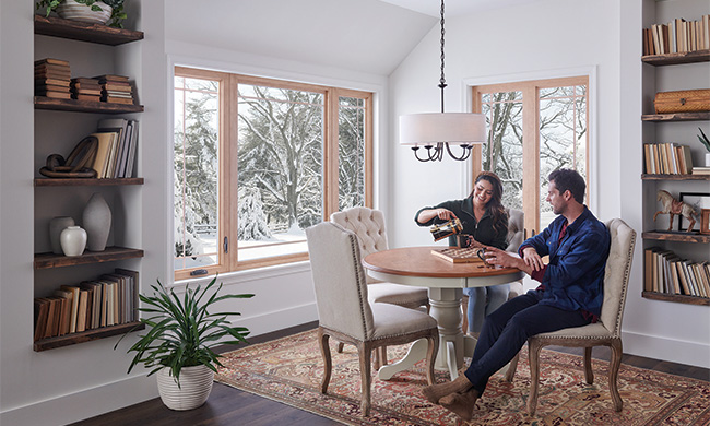 Cold Weather: Modern energy-efficient replacement windows installed in cozy winter home with snow visible outside, demonstrating cold weather comfort and insulation benefits